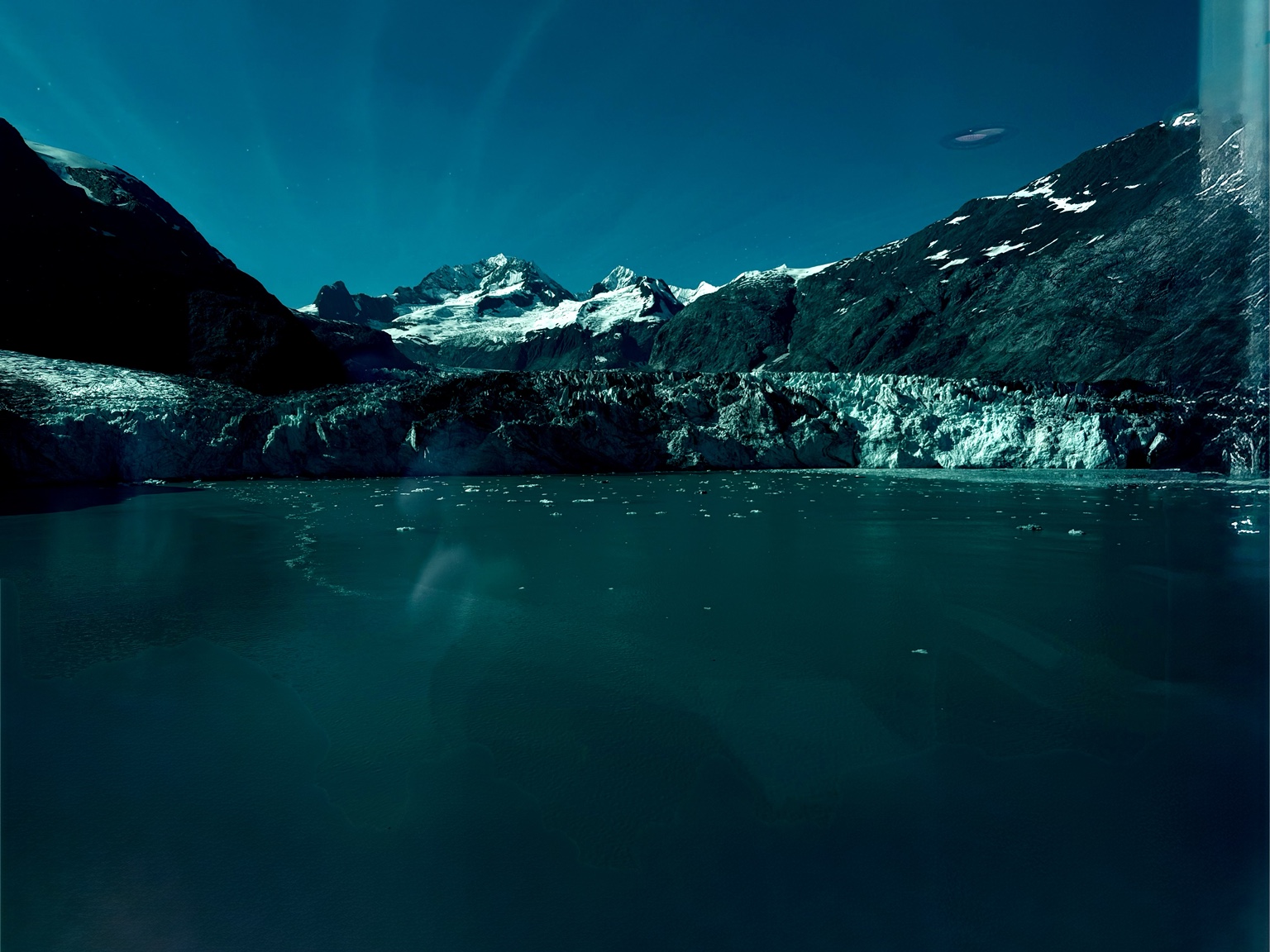 Glacier meeting the water beneath dark mountains